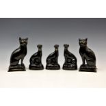 A pair of Victorian Staffordshire black glazed terracotta pottery cats, seated upon tasseled