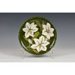 A Moorcroft Bermuda Lily pattern bowl, with white tubelined flowers against a green ground,