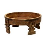 An Indian carved wooden grinding wheel stand, heavily carved throughout, on four shaped legs with