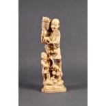 A Japanese carved ivory figure of a peach farmer, Meiji period (1868-1912), standing on rocks with a