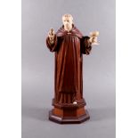 A French carved ivory and wood figure of a priest, 19th century, the priest with one hand raised,