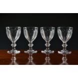 A set of four late Georgian wine goblets, the drawn cupped bowl with panel cut decoration, on a
