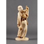 A Japanese carved ivory okimono of a puppeteer, Meiji period (1868-1912), holding a wooden frame