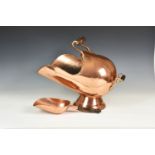 A copper helmet form coal scuttle, the scrolled uprights to turned wooden handle and rolled edge,