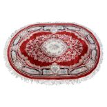 An oval Eastern Kayam OCM wool rug, 20th century, on red ground and guard border with floral main
