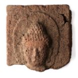 A VOLCANIC STONE PANEL DEPICTING THE HEAD OF BUDDHA, JAVA, 9TH/10TH CENTURY