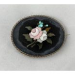 A vintage oval pietra dura floral design brooch in white metal frame, tests as silver