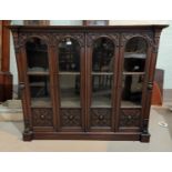 An Arts & Crafts mahogany bookcase enclosed by 4 arch panel doors, with fretted and beaded