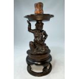 A Chinese bronze candlestick, the column in the form of a kneeling grotesque man supporting the
