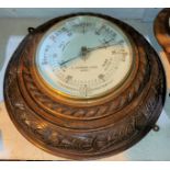 An early 20th century large circular aneroid barometer in oak wall hanging leaf carved rope twist