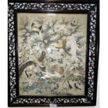 A Chinese finely woven silk embroidery depicting pairs of exotic birds in carved and pierced