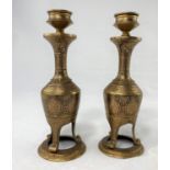 A pair of Indian candle sticks with detailed gilt decoration on tripod feet and base, height 17.5cm