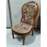 A Victorian carved walnut nursing chair with spoon back, in hand worked needlework fabric