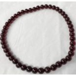 An amber bakelite bead necklace, cherry coloured, 65 cm approx, 103 gm, bead diameter 14 mm approx