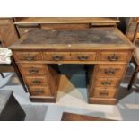 A 19th century oak kneehole desk with 8 pedestal and 1 central drawers with brass drop handles