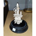 A carved bone miniature group of a woman spinning, under glass dome, height 14 cm (reputedly