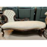 A Victorian carved walnut chaise longue with spoon and pierced scroll back, upholstered in cream