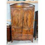 A late Georgian figured mahogany press cupboard, the upper section with arch top and 4 sliding trays