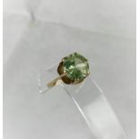 A yellow metal dress ring with citrine/peridot type stone in raised setting, tests as 9 ct, size N