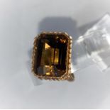 A 1970's yellow metal dress ring with ribbed decoration, set large cushion cut smoky quartz, 11