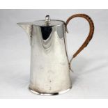 A hot water jug of tapering oval form, with cane bound handle, Chester 1916, 9.5oz. (296gm)