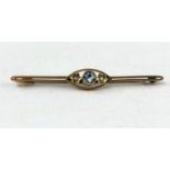 A yellow metal bar brooch set aquamarine coloured stone, flanked by 2 floral set seed pearls,