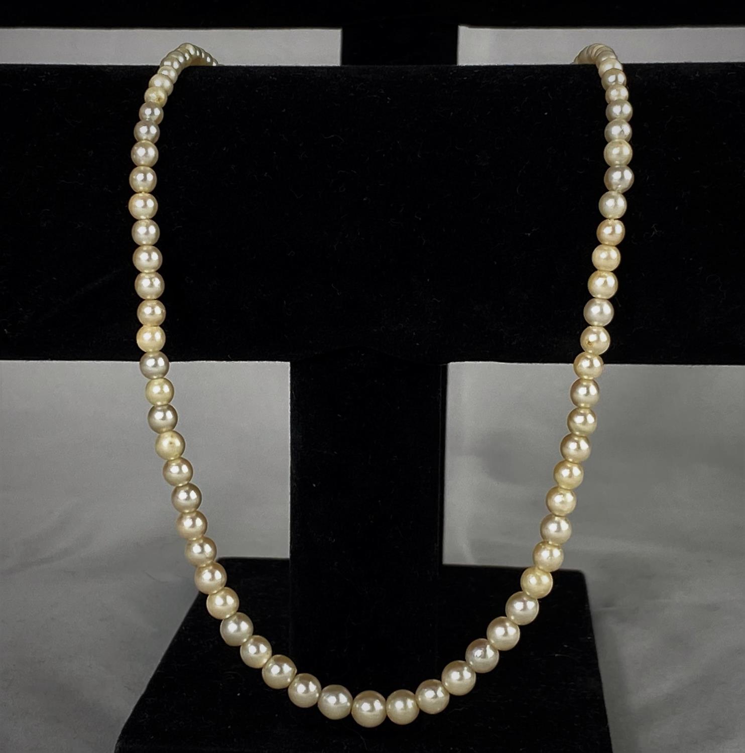 An early 20th century graduating cultured pearl necklace, the oval white metal clasp set with 2