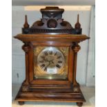 An Edwardian mantel clock in stained walnut architectural case with turned finials, brass dial and