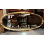 A large wall mirror in gilt oval frame decorated with roses in relief, length 176 cm