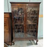 A 1920's mahogany Georgian style display cabinet enclosed by astragal glazed doors, on short