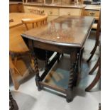 A 1930's oak drop leaf table with oval top on barley twist legs