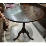 A Georgian oak tilt top occasional table on three splay feet