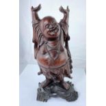 A Chinese carved wooden figure of smiling buddha with raised arms, on ebonized base, height 38cm and