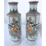 A pair of Chinese ceramic rouleau vases decorated with traditional family scenes, hand painted