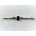 An Edwardian white and yellow metal bar brooch set oval sapphire, unmarked, tests as circa 18ct, 2.5