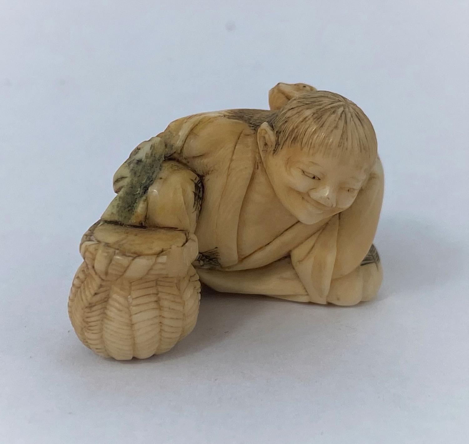 A Japanese netsuke, man reclining with frog on back, missing one arm