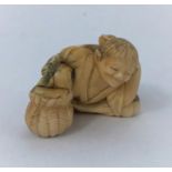 A Japanese netsuke, man reclining with frog on back, missing one arm