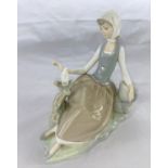 A Lladro group of young woman seated looking at a dove