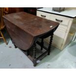 A 1930's oak gate leg dining table, with oval top, on barley twist legs