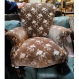 A Victorian armchair in embossed floral fabric with low back