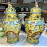 A Chinese pair of baluster covered vases with temple dog finials, mask and ring side handles,
