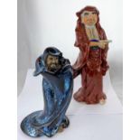 Two Oriental ceramic figures of men in cloaks, one with red glaze, the other mottled blue and brown,