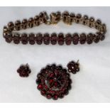 A late Victorian/Edwardian suite of garnet jewellery: double row bracelet, circular tiered brooch