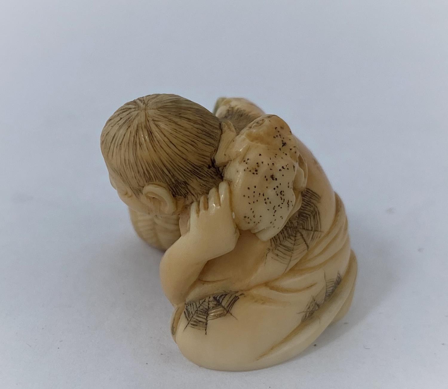 A Japanese netsuke, man reclining with frog on back, missing one arm - Image 2 of 5