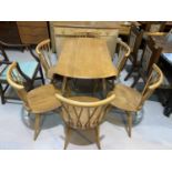 A 1960's Ercol light elm dining suite comprising drop leaf circular table, 5 stick back chairs and