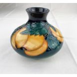 A squat circular Moorcroft vase decorated with apricot type fruit & green leaves impressed