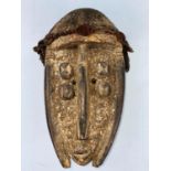 An African tribal carved and painted wood mask with applied fabric head covering 32cm