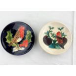 2 Moorcroft pin dishes one decorated with robin on holly twig, the other with a bird, leaves & plums