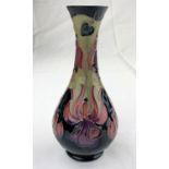 A Moorcroft baluster slender neck vase decorated with stylized flowers in purple, red & green