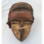 An African tribal carved and painted wood mask, applied rope basketry and cloth headdress, damage to